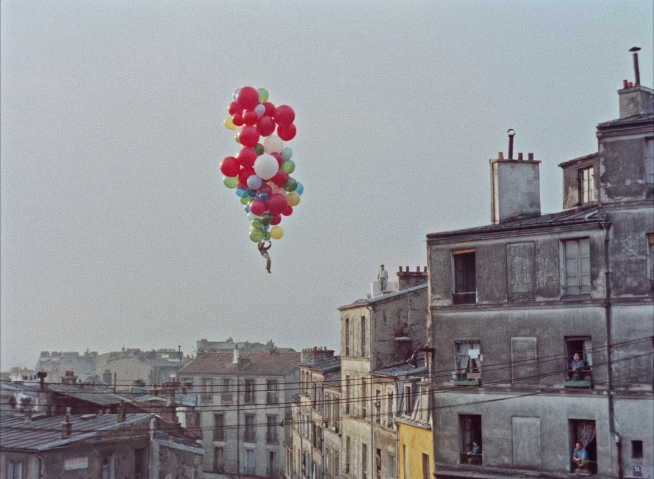 The Red Balloon (1956) movie still: wide — A dense urban landscape features aging residential buildings with gray facades and chimney pots. A child…