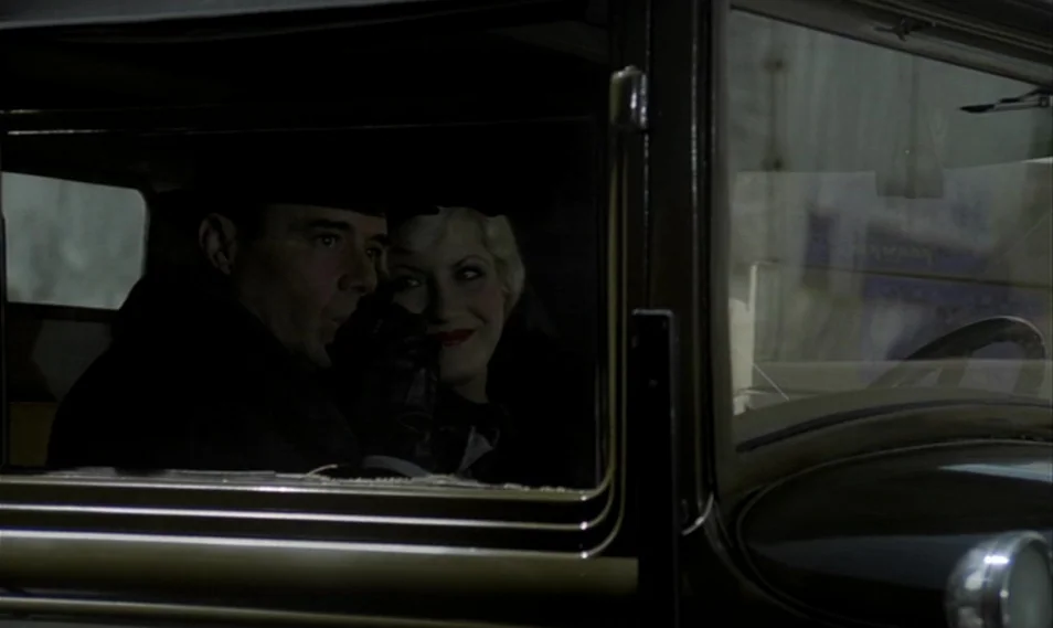 Despair (1978) movie still: medium — A dark, vintage automobile interior at night with limited ambient light from outside. A man and a blonde woman…