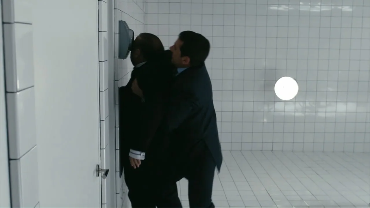 Get Smart (2008) movie still: medium — A stark room with floor-to-ceiling white ceramic tiles and a single wall-mounted light. One man in a dark…