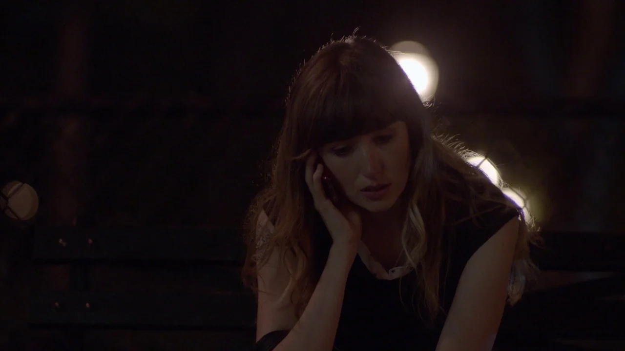 The Heart Machine (2014) movie still: closeup — A woman sits on a bench in the dark with blurred circular bokeh lights behind. She holds a…