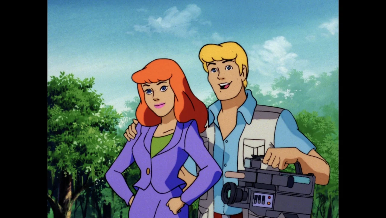 Scooby-Doo on Zombie Island (1998) movie still: medium — A lush green outdoor park setting features trees and a clear blue sky. A young couple poses…