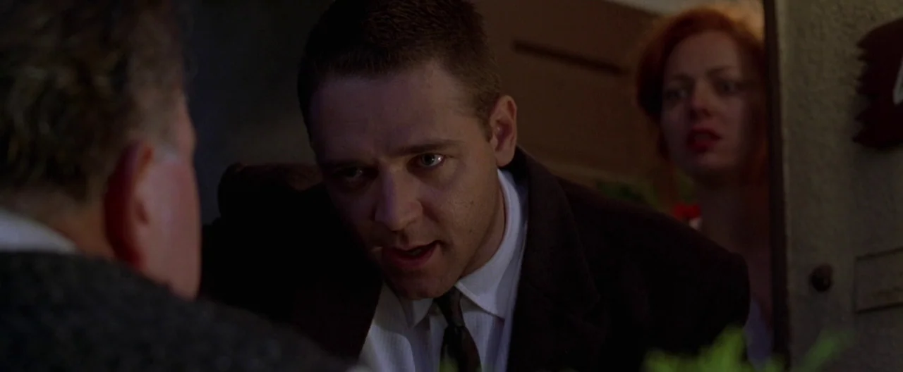 L.A. Confidential (1997) movie still: medium — A dimly lit residential doorway provides a frame for two individuals in conversation. A man faces the…