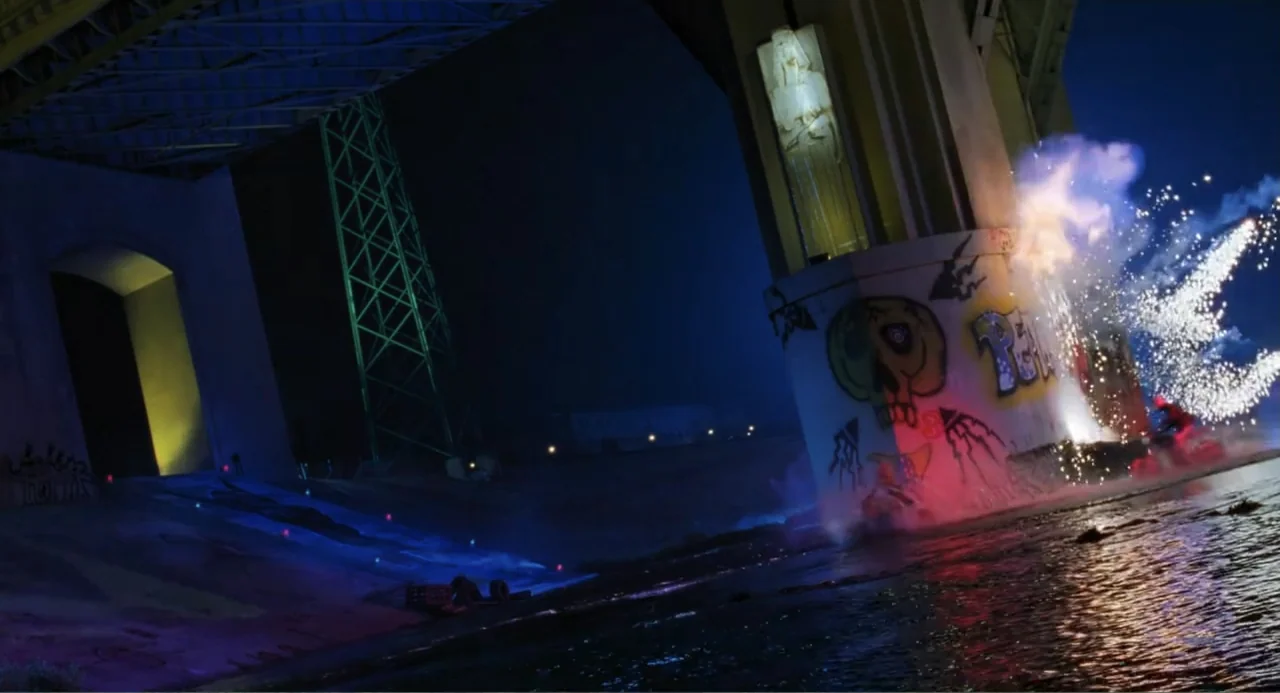 Batman & Robin (1997) movie still: wide — A dark bridge underpass features massive concrete piers marked with prominent colorful spray-painted…