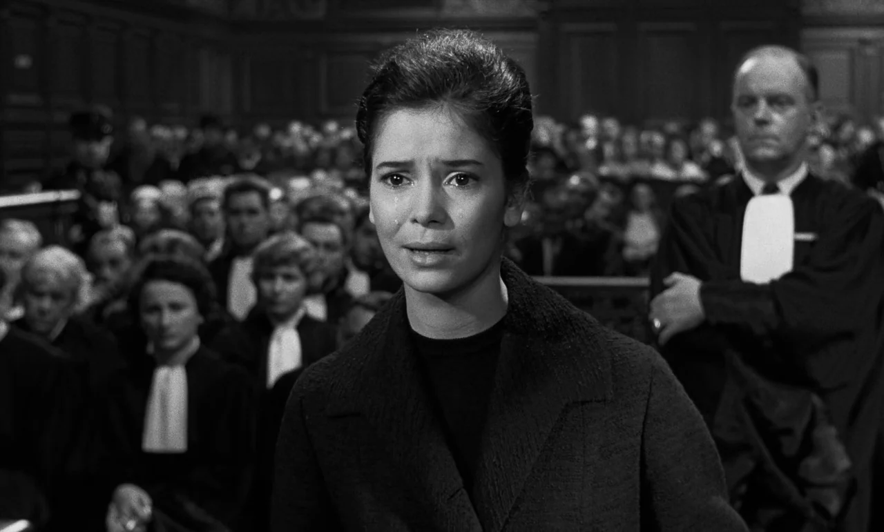 La Verite (1960) movie still: medium — A crowded wooden courtroom features rows of seated people in formal legal attire. A young woman in a dark…