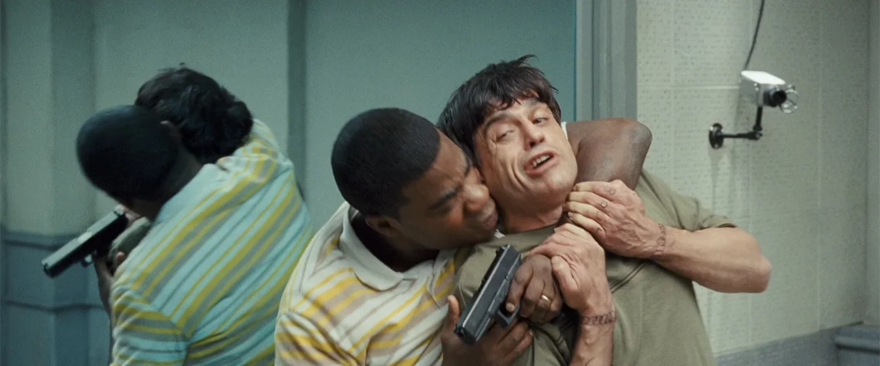 Cop Out (2010) movie still: medium — A sterile building corridor features light green walls and a mounted security camera.