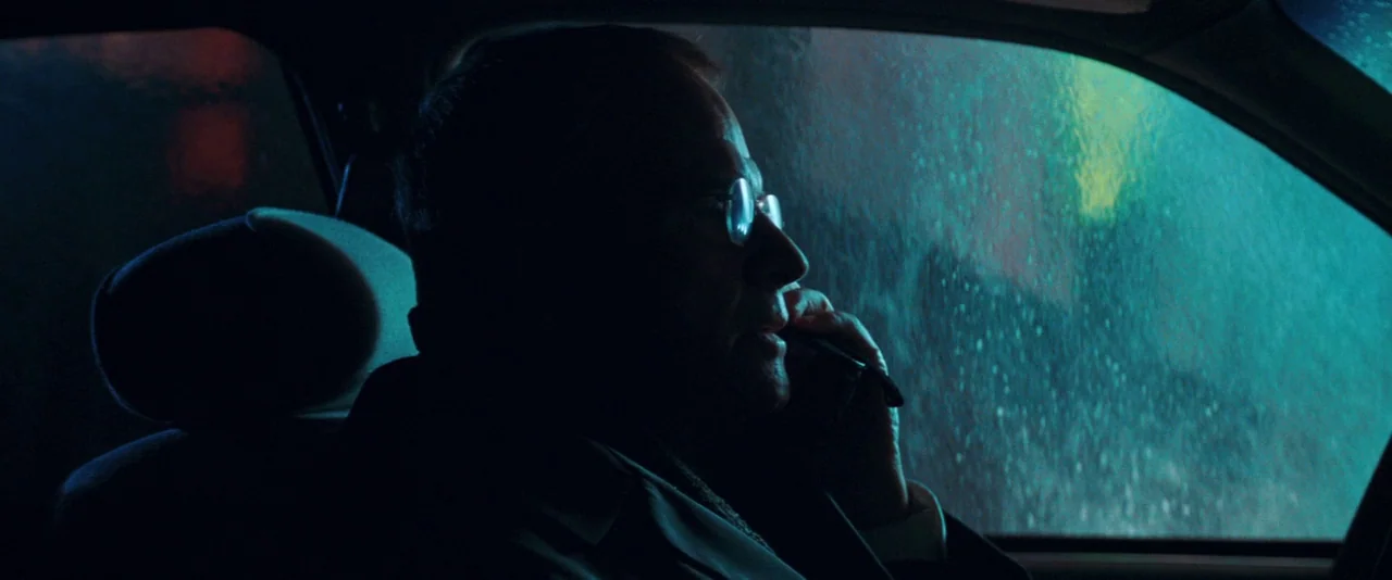 The Sweet Hereafter (1997) movie still: medium — The interior of a moving car is dark, illuminated by rain-blurred city lights outside. A man in his…