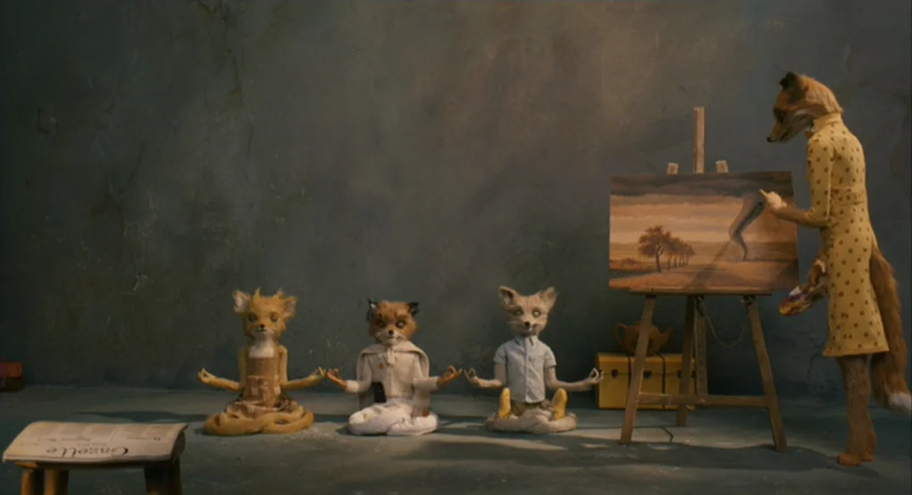 Fantastic Mr. Fox (2009) movie still: wide — A studio space with a textured blue-gray wall contains several fox-like figures. Three foxes sit in…