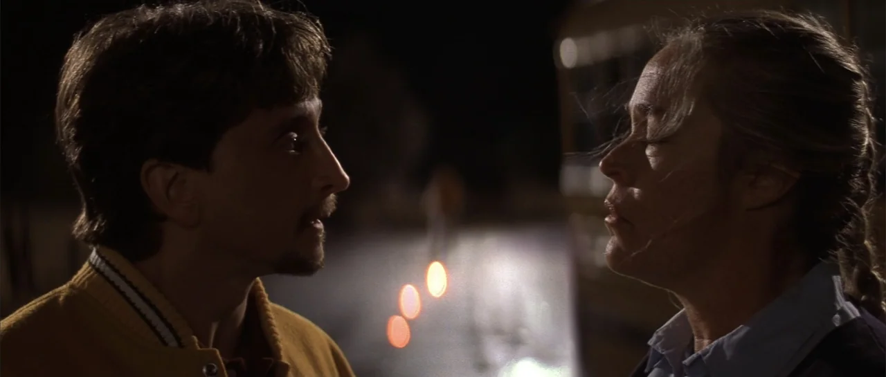 Jeepers Creepers 2 (2003) movie still: medium — A dark outdoor parking lot at night features a man and woman in conversation. The two subjects face…