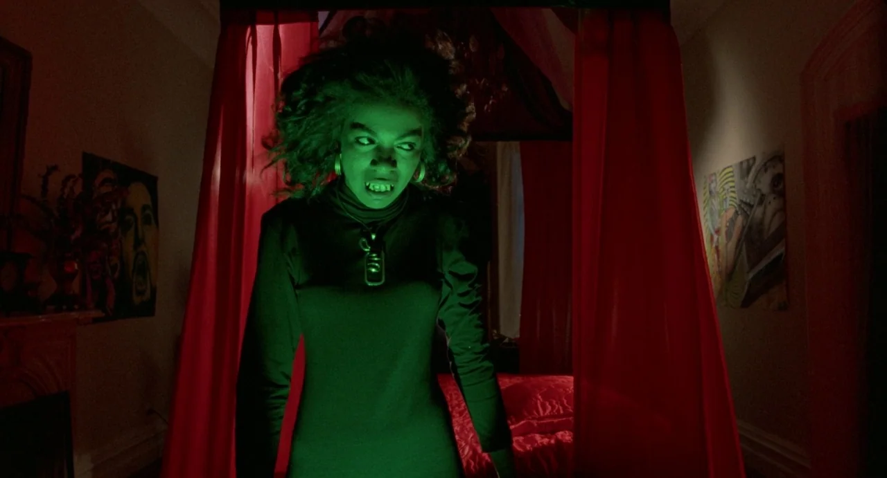 Def By Temptation (1990) movie still: medium — A dim room features a canopy bed framed by bright red curtains. A woman stands between the fabric,…