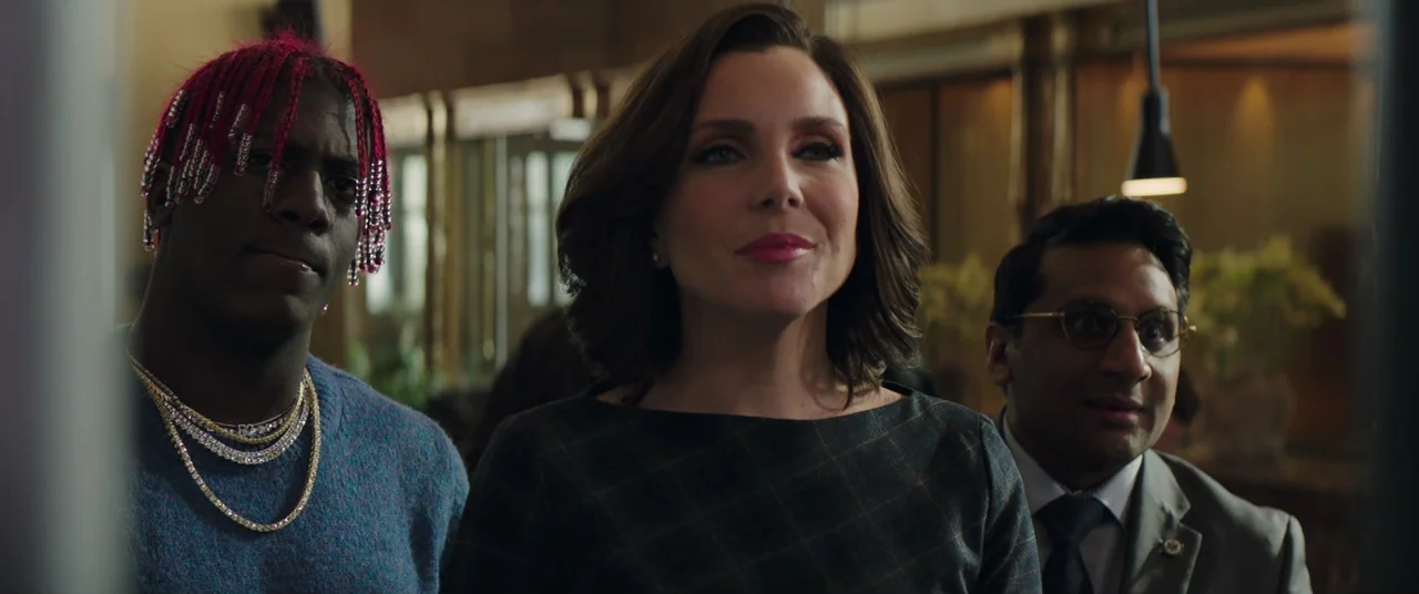Long Shot (2019) movie still: medium — A group of three people stand together inside a polished, dimly lit public space. They gaze forward while…