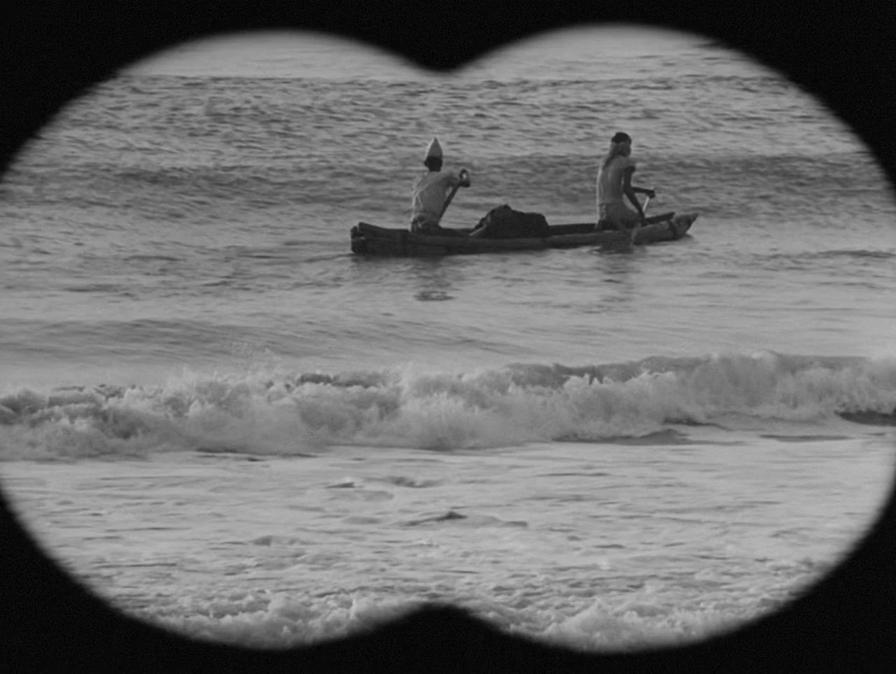 Charulata (1964) movie still: wide — A view through binoculars showing two men in a wooden canoe on the ocean. The men paddle across rolling waves…