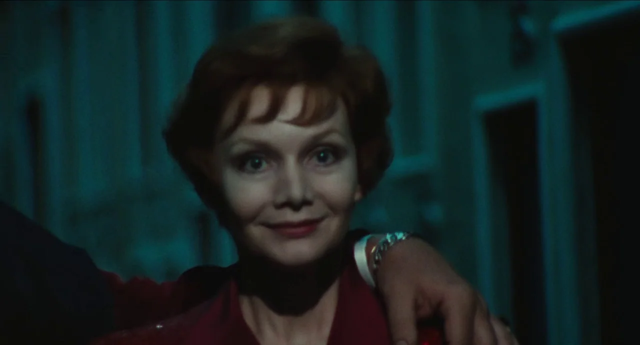 City of Women (1980) movie still: closeup — A woman is positioned in a dimly lit, narrow corridor with blue-toned shadows. An arm rests on her…