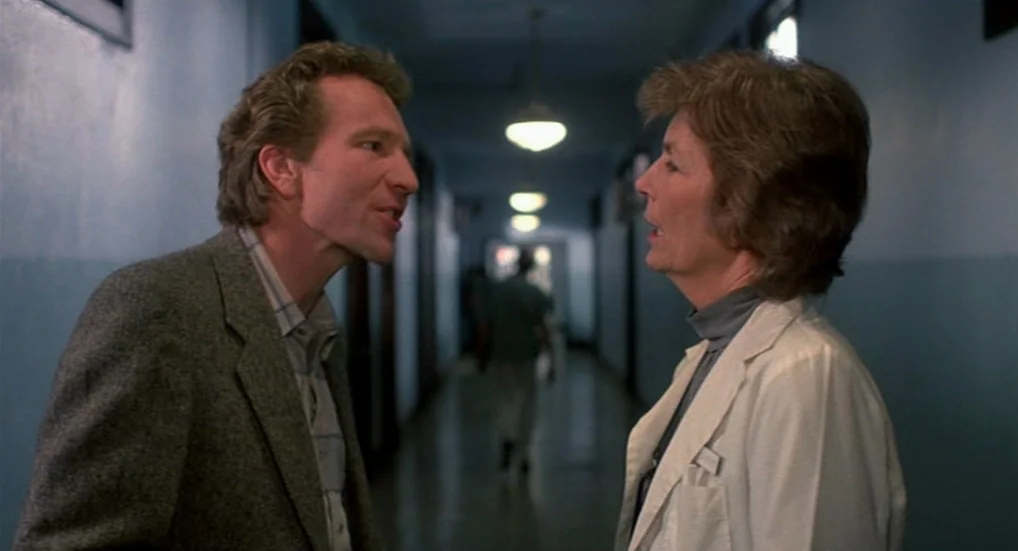 A Nightmare On Elm Street 3: Dream Warriors (1987) movie still: medium — A long institutional hallway with blue walls and overhead lights creates a…