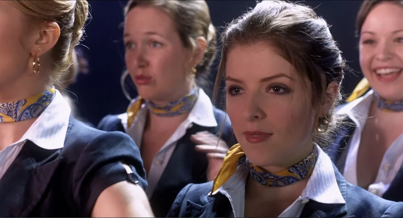 Pitch Perfect (2012) movie still: medium — Three flight attendants are positioned in a group against a dark background. They are wearing matching…