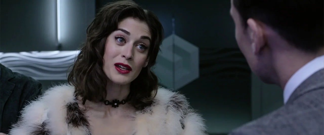 Now You See Me 2 (2016) movie still: medium — A modern corporate office space features a dark wall with a subtle geometric logo pattern. A woman in…