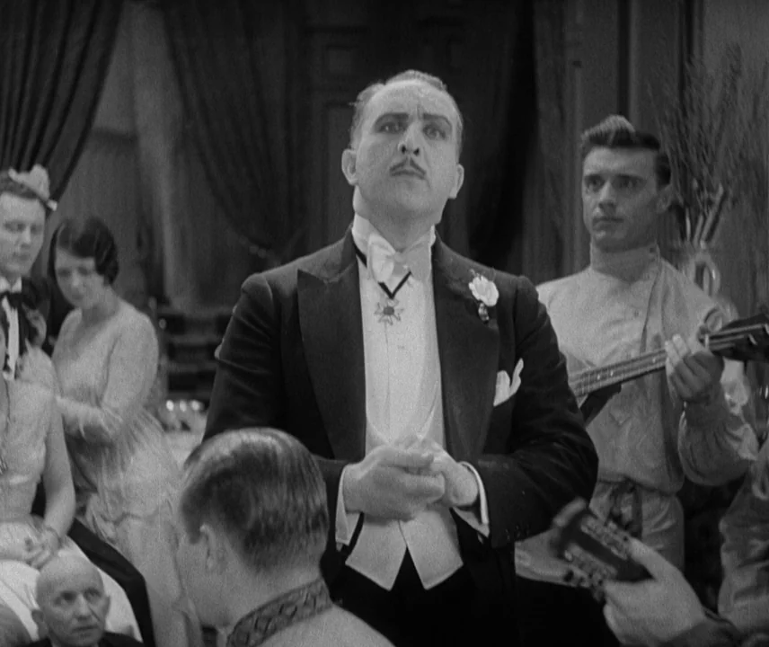 City Lights (1931) movie still: medium — An ornate interior space filled with guests in formal attire at a social event. A man in a tailcoat stands…