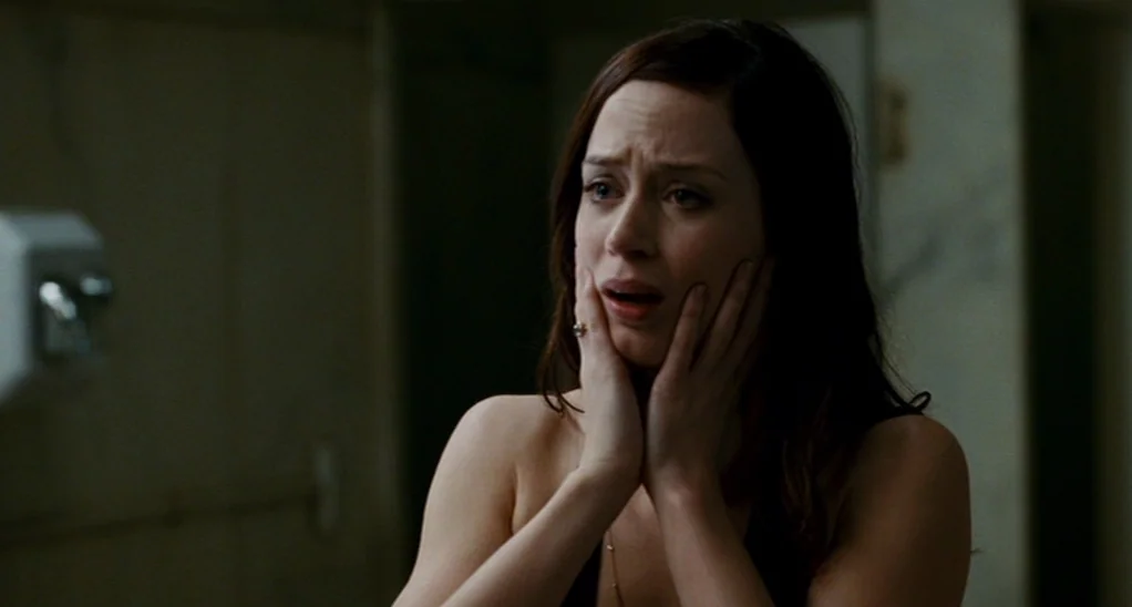 The Adjustment Bureau (2013) movie still: closeup — A dimly lit room with stone walls and a blurred dispenser visible on the left. A young woman…