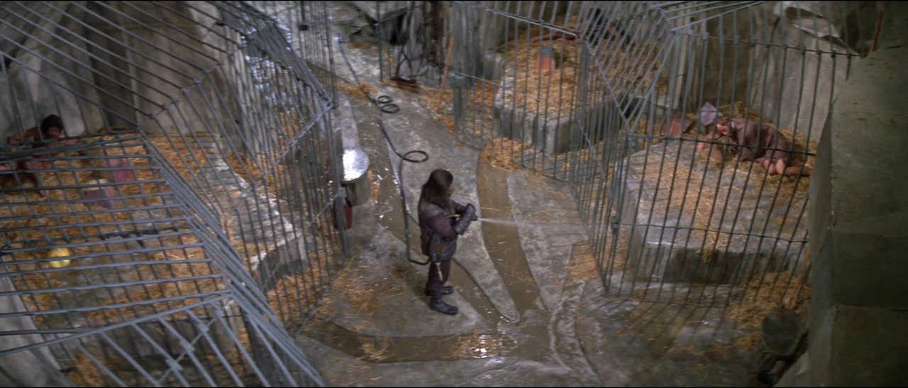 Planet of the Apes (1968) (1968) movie still: wide — A subterranean facility features multiple stone pens enclosed by vertical metal bars and straw.…