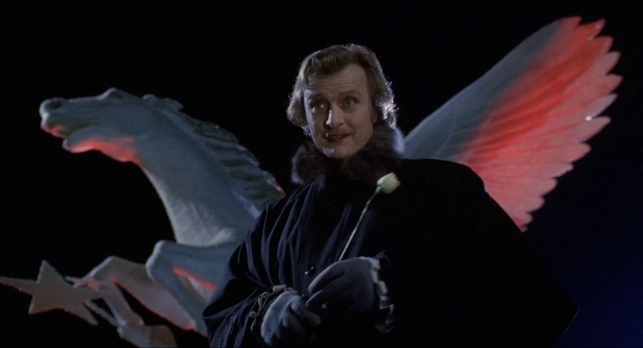 Buffy the Vampire Slayer (1992) movie still: medium — A dark night setting featuring a large lit sculpture of a winged horse. A man in period…