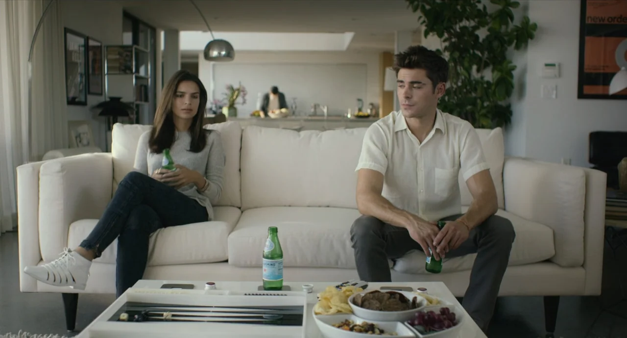 We Are Your Friends (2015) movie still: medium — A modern, bright living room features a white sofa, a coffee table with snacks, and large green…
