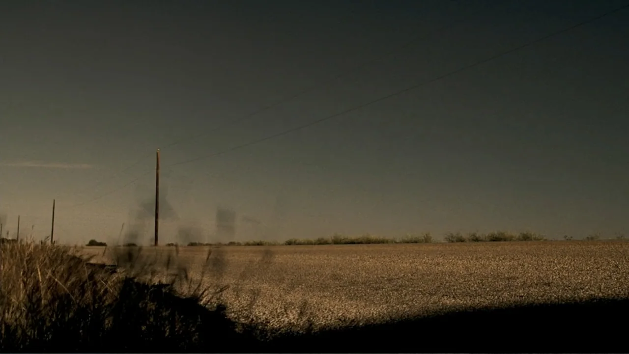 The Texas Chainsaw Massacre: The Beginning (2006) movie still: establishing — An asphalt road extends into a flat landscape under a clear horizon.…