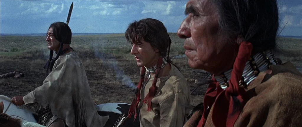 Little Big Man (1970) movie still: medium — A vast, flat prairie landscape under a daytime sky with scattered clouds. Three men are mounted on…