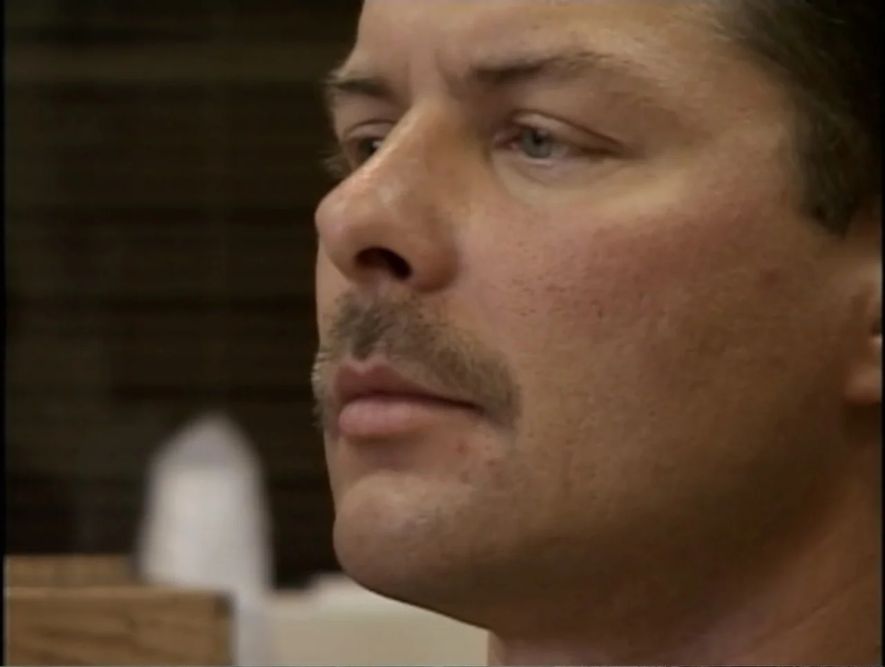 A Rape in a Small Town: The Florence Holway Story (2005) movie still: closeup — An interior space with a dark brick wall visible in the soft-focus…