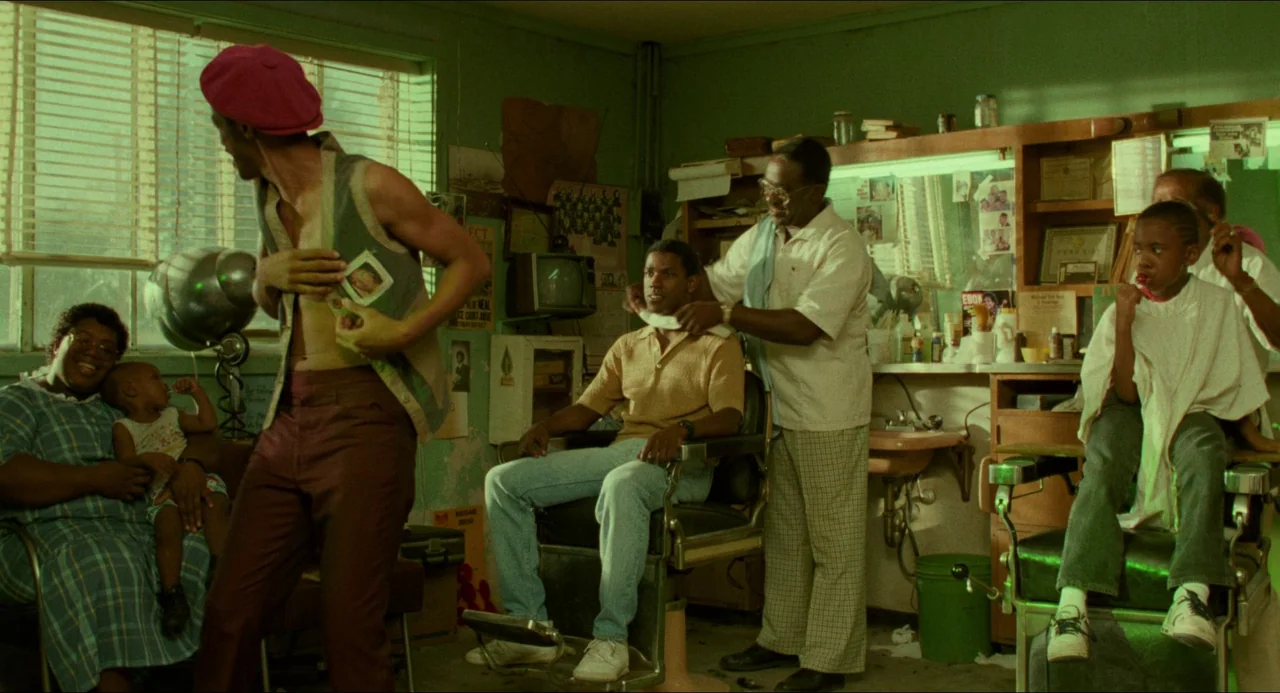 Mississippi Masala (1991) movie still: medium — A cluttered barbershop interior with green walls, shelves filled with hair products, and posters. A…