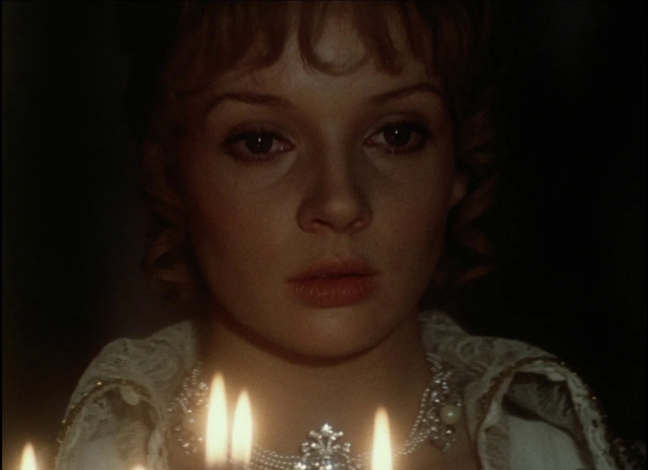Beauty and the Beast (1979) movie still: closeup — The dark space is dimly lit by flickering candles placed near the camera. A young woman wears an…