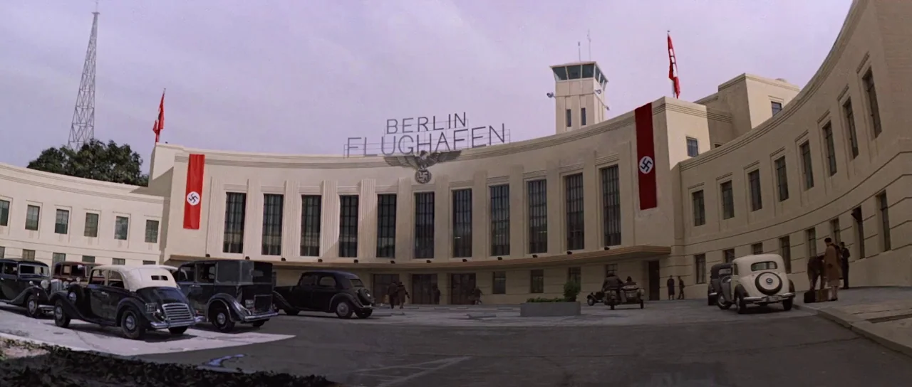 Indiana Jones and the Last Crusade (1989) movie still: establishing — A cream-colored Art Deco airport terminal features large windows and red Nazi…