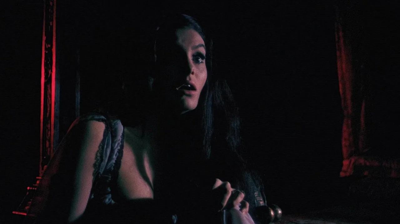 The Whip and The Body (1963) movie still: medium — A dark bedroom with red accents visible in the background and foreground shadows. A woman looks…