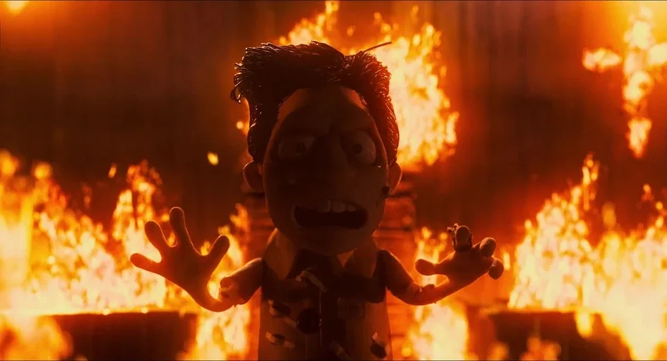Memoir of a Snail (2024) movie still: A stop-motion character stands trapped in a literal hellscape, framed by roaring flames that consume the…