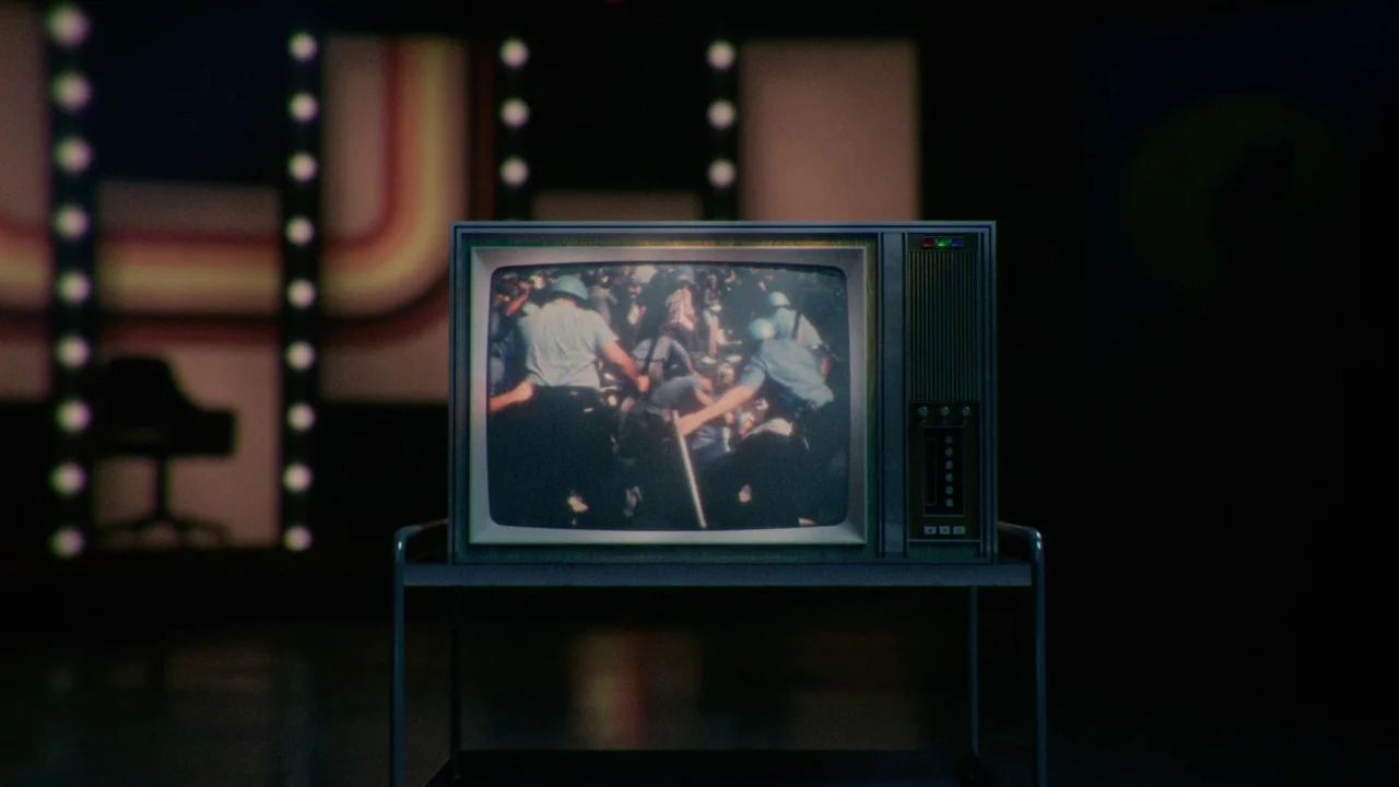 Late Night With The Devil (2023) movie still: medium — A vintage CRT television sits on a metal cart in a dark studio. The screen shows black and…