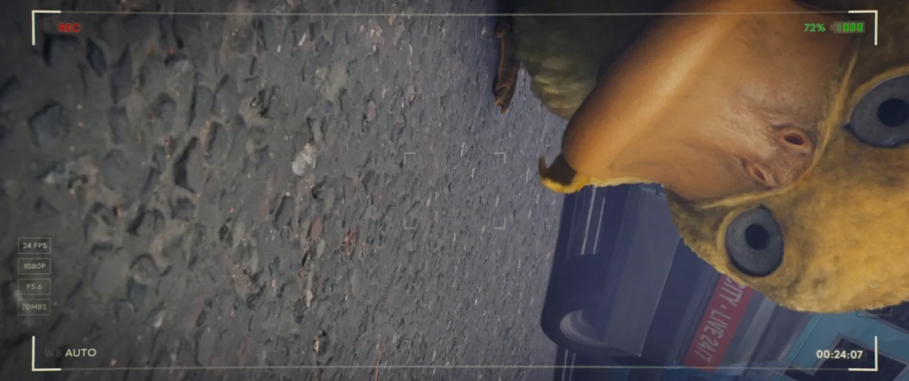 Pokémon Detective Pikachu movie still: closeup — The frame depicts a low angle view from a digital camera pointed at the ground. A yellow creature…
