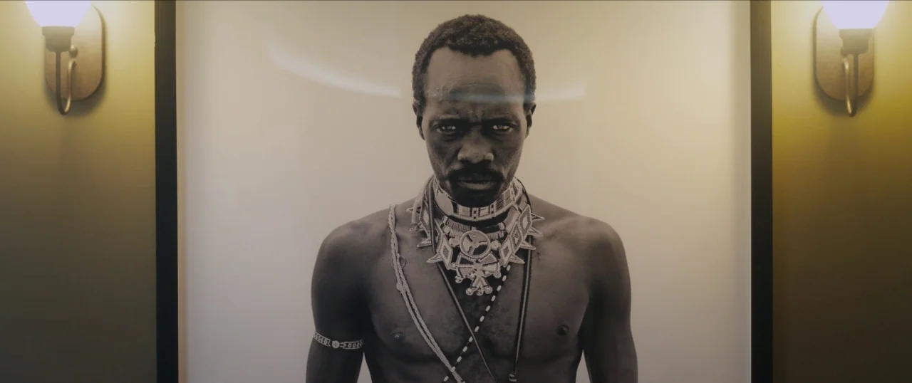 Da Sweet Blood of Jesus (2014) movie still: medium — A framed black-and-white portrait of a man hangs on a painted wall. Two golden wall sconces…