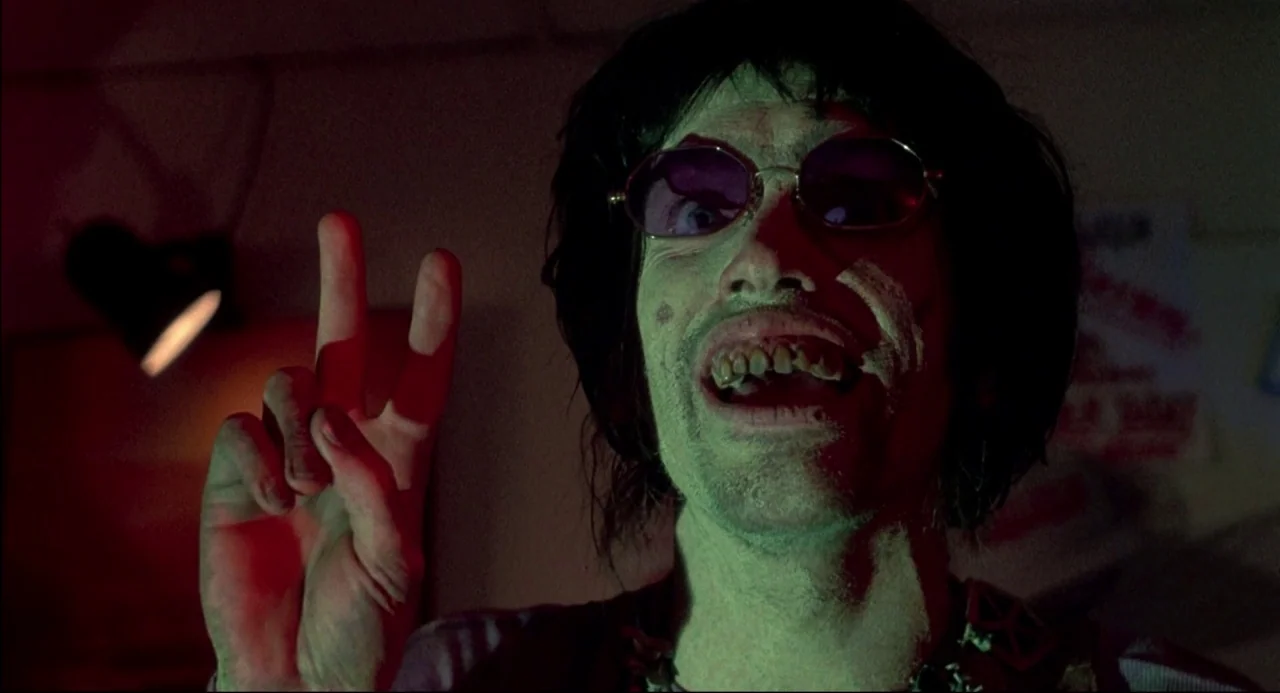 The Texas Chainsaw Massacre 2 (1986) movie still: closeup — A dark, dimly lit indoor space with low-key illumination casting deep, sharp shadows. A…