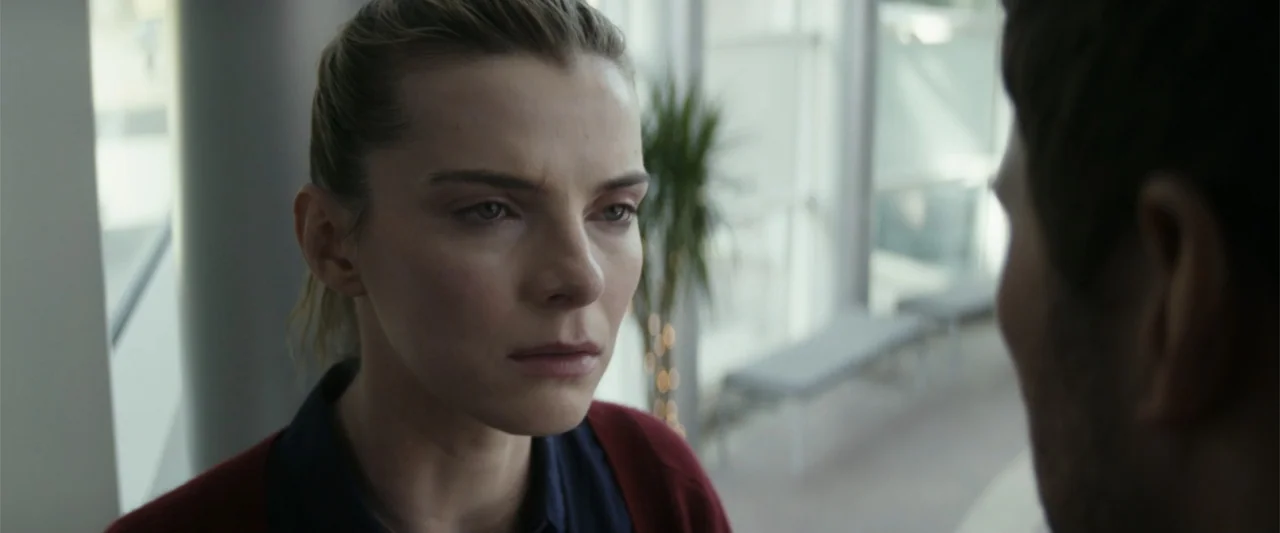 The Tomorrow War (2021) movie still: closeup — A well-lit office interior with large glass windows and an indoor plant visible. A woman with her…
