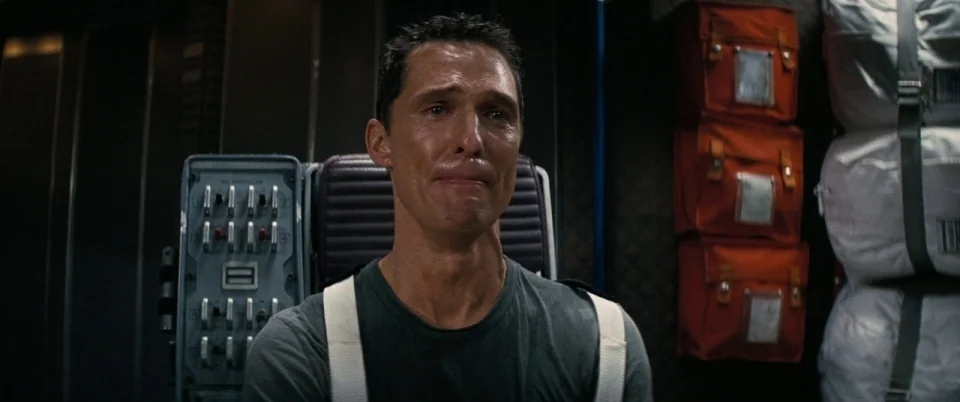 Interstellar (2014) movie still: medium — The interior of a spaceship cabin features dark technical panels and wall-mounted orange storage gear. A…