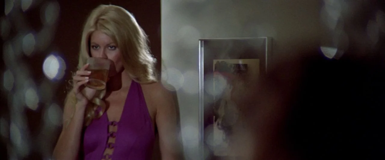 Soylent Green (1973) movie still: medium — A dimly lit residential apartment interior features a woman standing against a neutral wall. The woman is…
