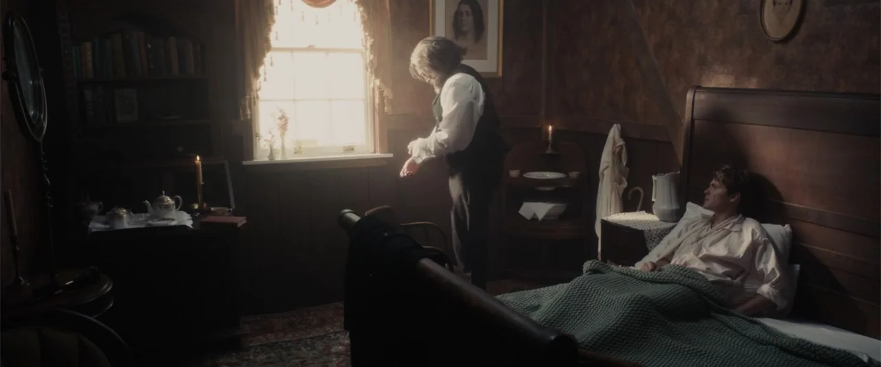 I Heard the Bells (2022) movie still: wide — A 19th-century bedroom features dark wood paneling, antique furniture, and a single bright window. An…