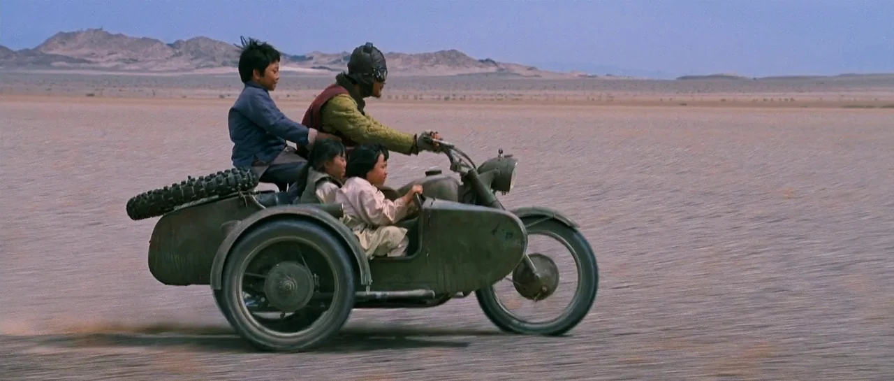 The Good The Bad The Weird (2008) movie still: wide — A vast, flat, arid desert landscape under a clear blue sky. A man rides an olive green…