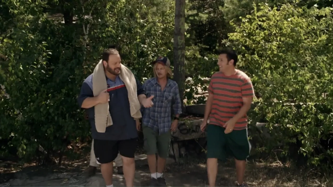 Grown Ups 2 (2013) movie still: fullbody — A group of three men walk together on a path surrounded by dense trees. They are engaged in conversation…