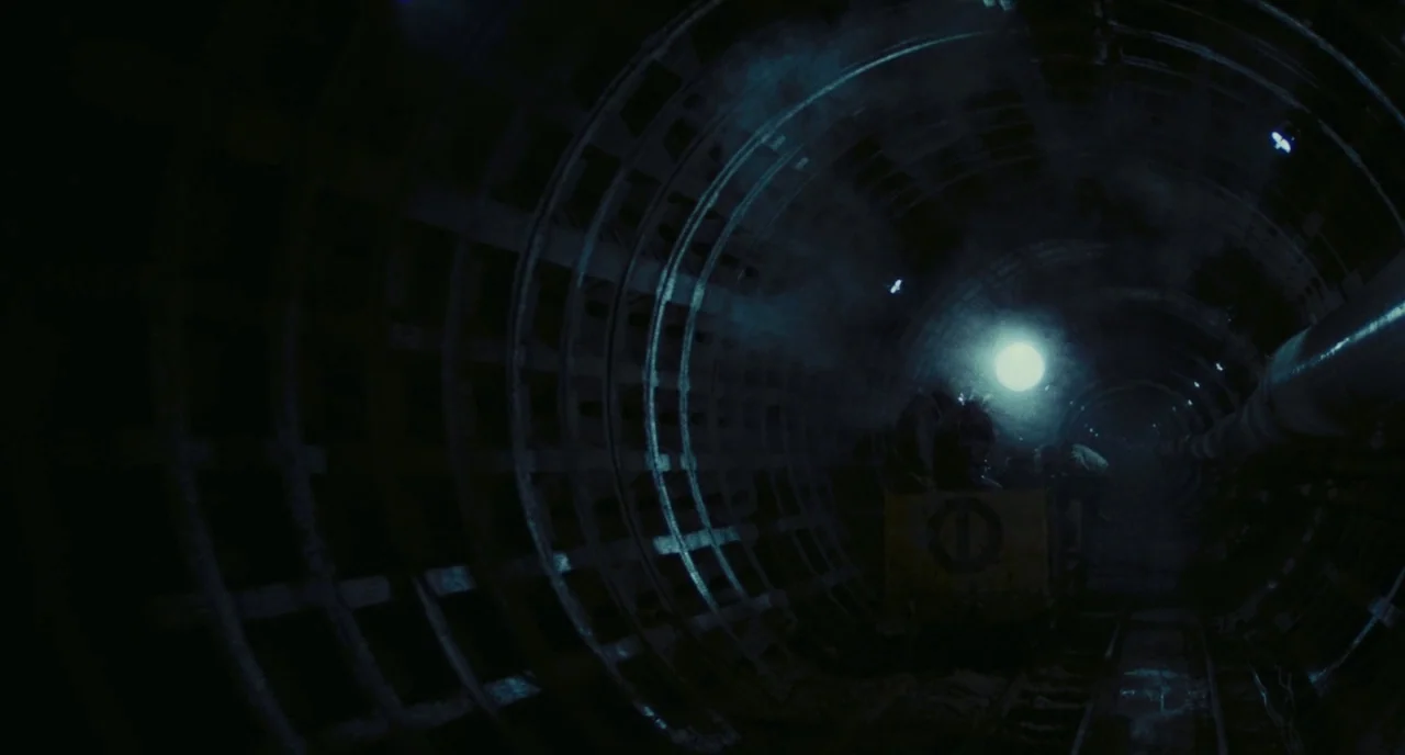 Roma (1972) movie still: wide — A long, circular subterranean tunnel is constructed from exposed iron ribbed segments. A bright light source glows…