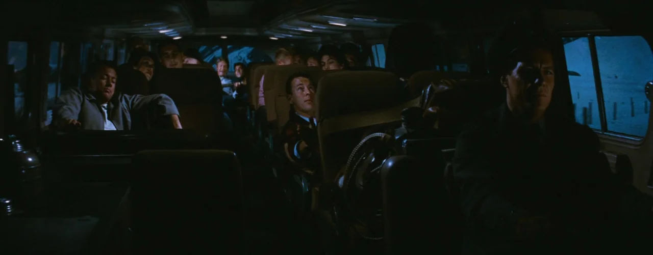 Bus Stop (1956) movie still: wide — The interior of a darkened bus is filled with passengers in various seats. Blue light filters through the side…