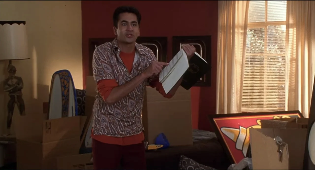 National Lampoon's Van Wilder (2002) movie still: medium — A cluttered room containing cardboard moving boxes, artwork, and a floor lamp by a…