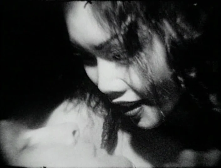 Cowards Bend The Knee (2003) movie still: closeup — A close-up shot of two people in a dark room. One person looms over the other while they are…