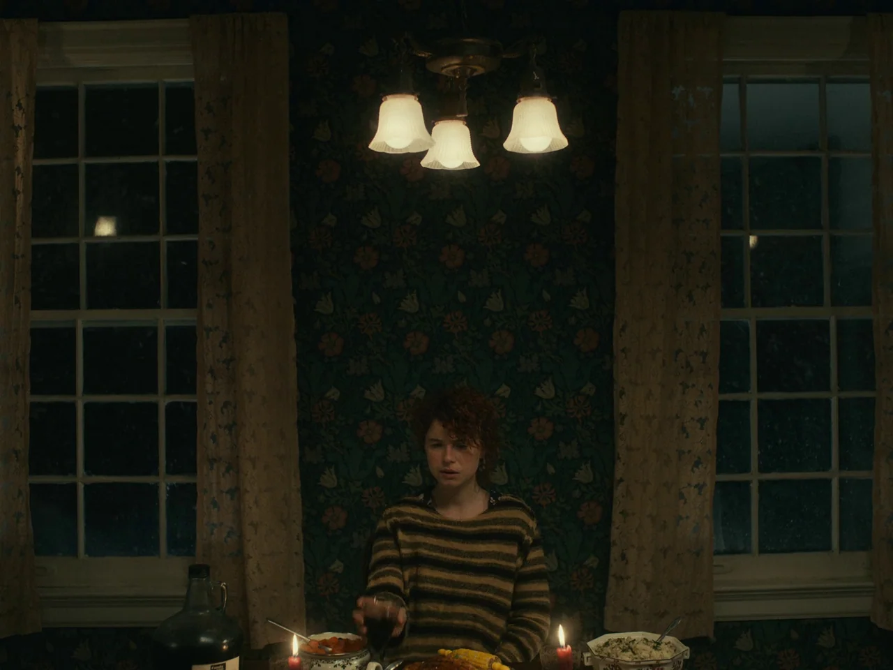 I’m Thinking of Ending Things (2020) movie still: medium — A dining room features floral patterned wallpaper and two windows flanking the central…