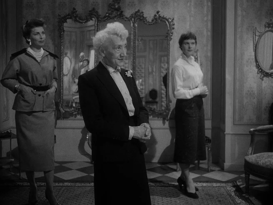 Dreams (1955) movie still: fullbody — An elegant, light-toned room features patterned wallpaper and a large, ornate three-panel mirror. Three women…