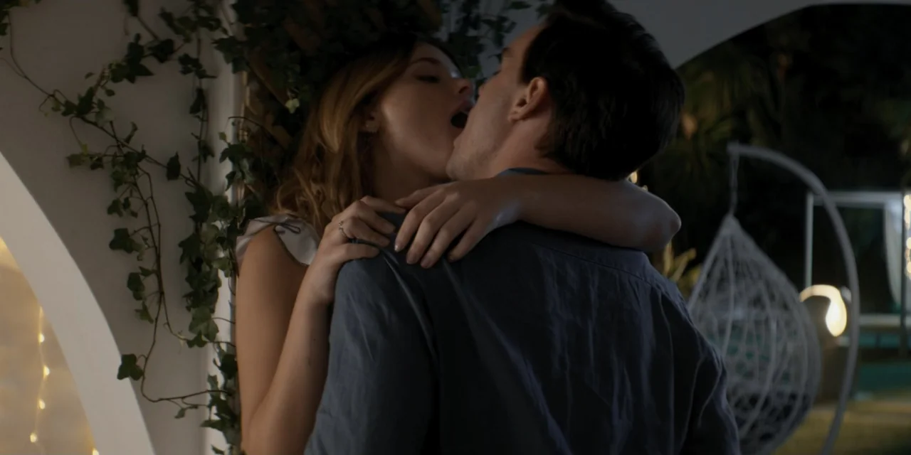 Your Fault (2024) movie still: medium — An outdoor patio features a stone column covered in lush green climbing ivy. A young man and woman stand…