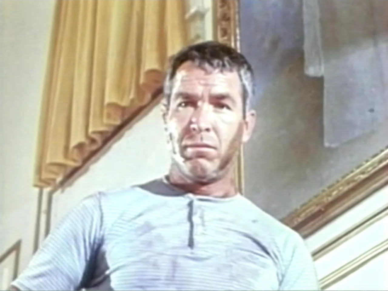 In the Year 2889 (1969) movie still: medium — An interior space features pale walls, a gold-curtained window, and a large framed painting. A man in…
